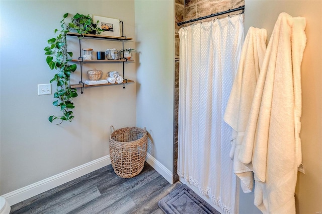 full bathroom with a shower with shower curtain, baseboards, and wood finished floors