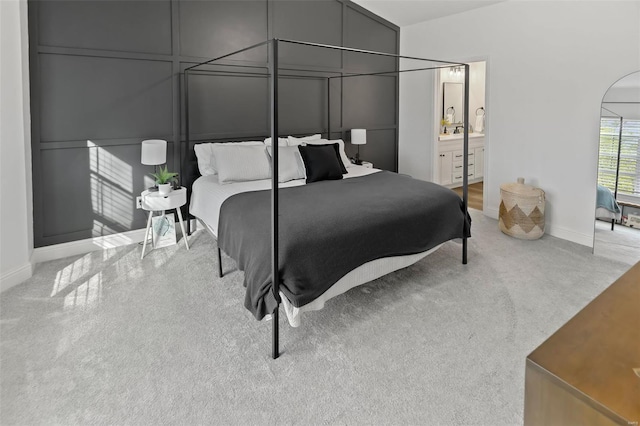 carpeted bedroom featuring baseboards and connected bathroom