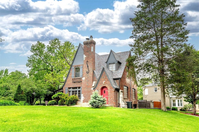 tudor-style house with brick siding, a chimney, and central AC unit