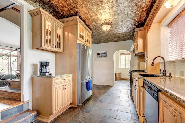 kitchen featuring appliances with stainless steel finishes, arched walkways, an ornate ceiling, a sink, and glass insert cabinets