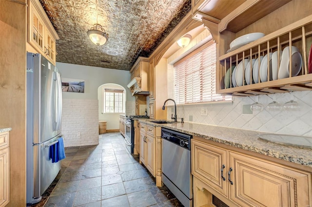 kitchen with stainless steel appliances, a sink, open shelves, arched walkways, and stone tile flooring