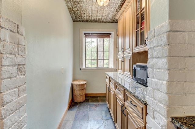 bar area with baseboards, stone tile flooring, and black microwave