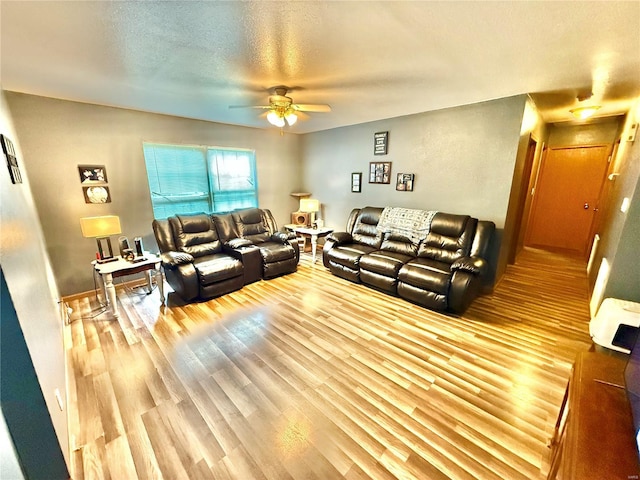 living room with a ceiling fan, wood finished floors, and a textured ceiling