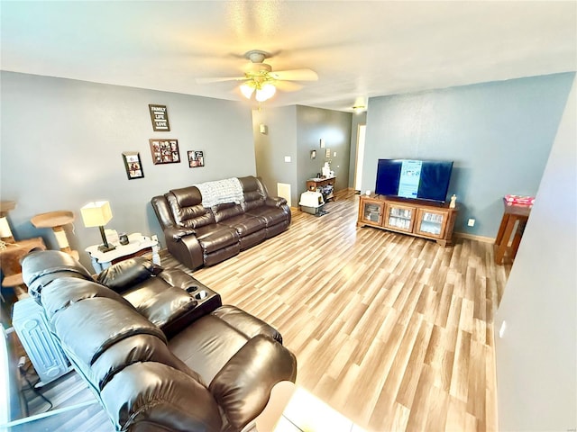 living area featuring a ceiling fan, wood finished floors, and baseboards