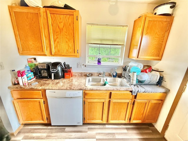kitchen with a sink, light wood finished floors, light countertops, and white dishwasher