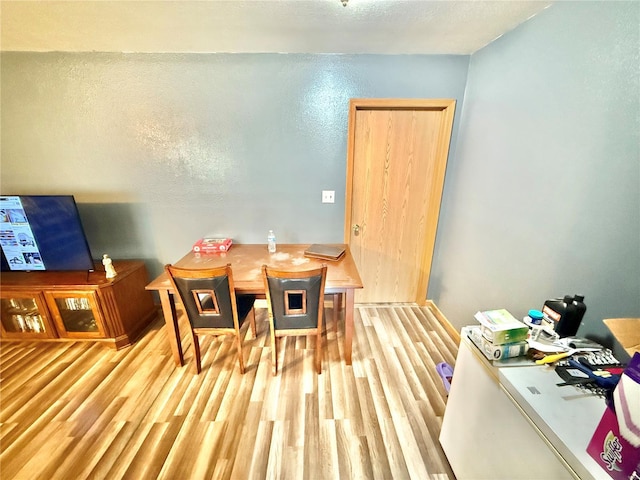 dining area with light wood-style floors and a textured ceiling