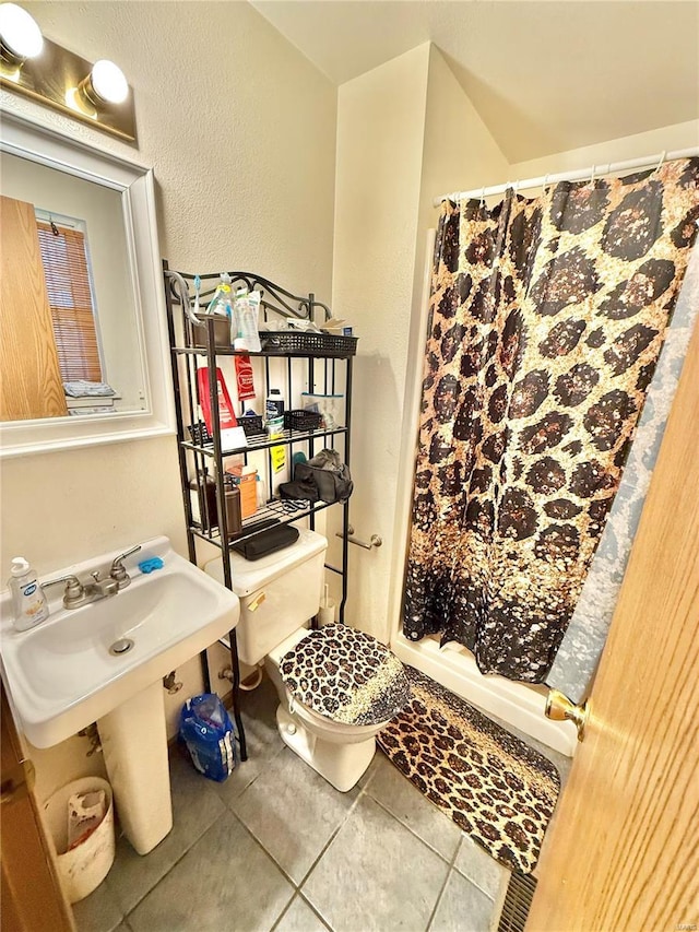 bathroom with toilet, a stall shower, a textured wall, and tile patterned floors