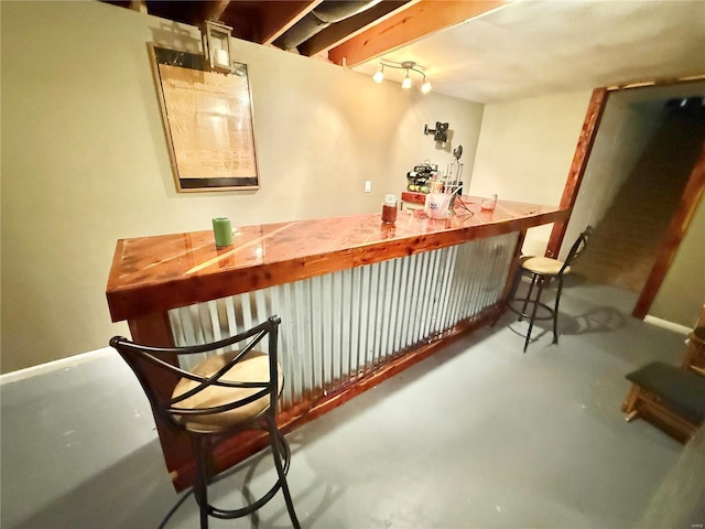 bar featuring baseboards, a bar, and finished concrete floors