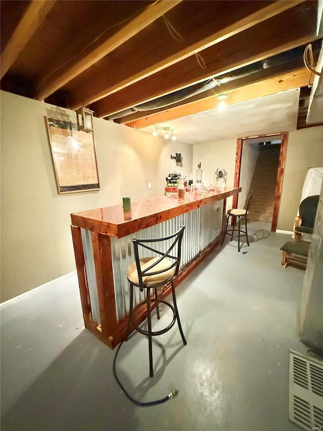 bar with concrete floors, a bar, and baseboards