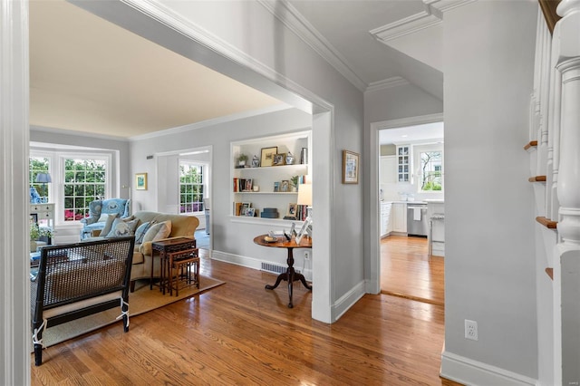 interior space featuring visible vents, light wood-type flooring, ornamental molding, and baseboards