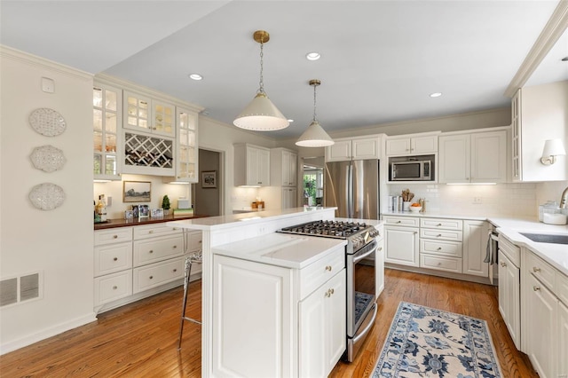 kitchen with light wood-style floors, visible vents, backsplash, a kitchen island, and appliances with stainless steel finishes