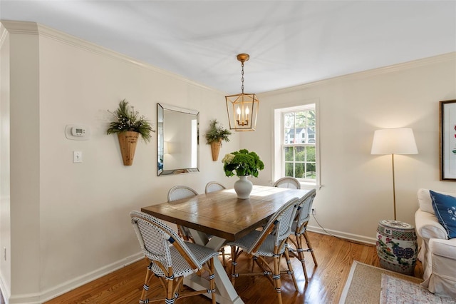 dining room with baseboards, light wood-type flooring, a chandelier, and crown molding