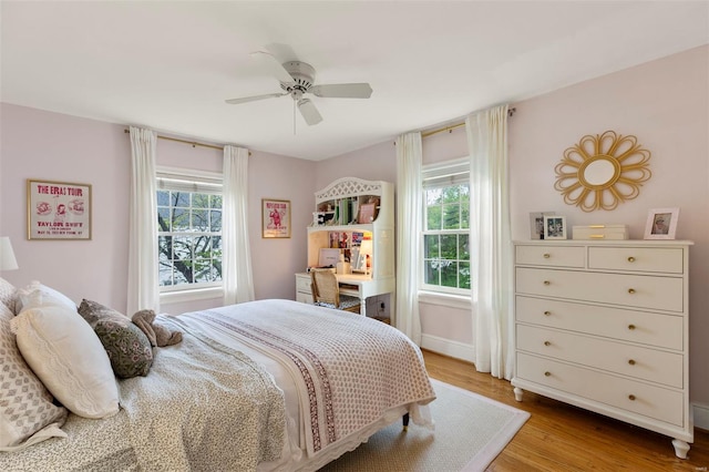 bedroom featuring multiple windows, ceiling fan, wood finished floors, and baseboards