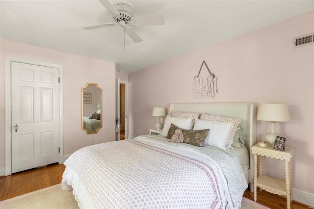 bedroom featuring visible vents, ceiling fan, wood finished floors, and baseboards