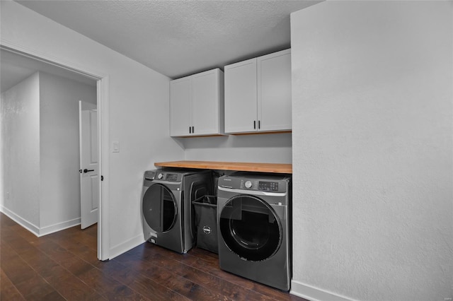 washroom with washer and dryer, cabinet space, a textured ceiling, baseboards, and dark wood-type flooring