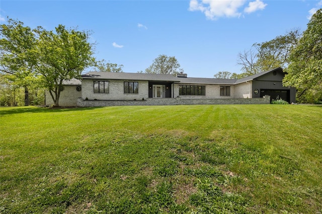 rear view of house featuring a yard, brick siding, and a garage