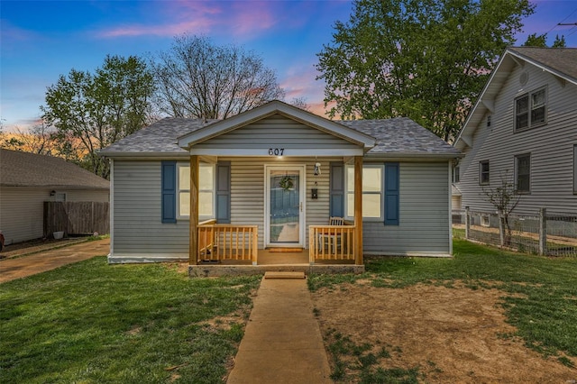 bungalow with a porch, a front yard, and fence