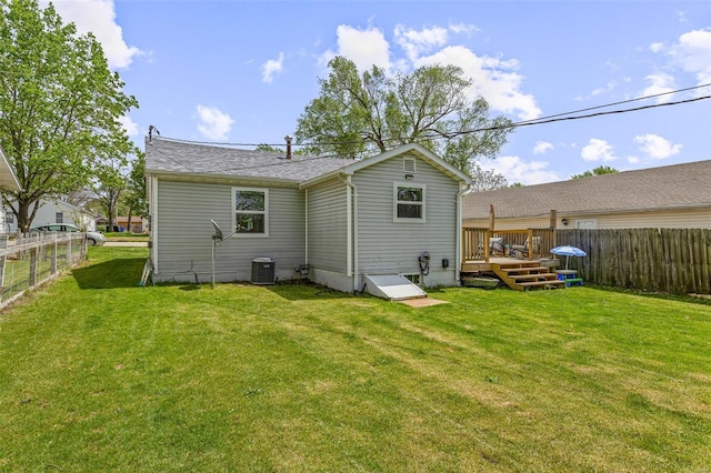 rear view of property with a deck, fence, cooling unit, and a lawn