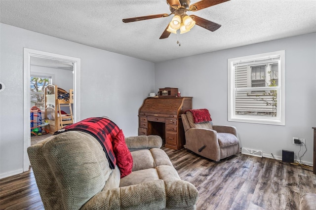 living room with a ceiling fan, visible vents, baseboards, a textured ceiling, and wood finished floors