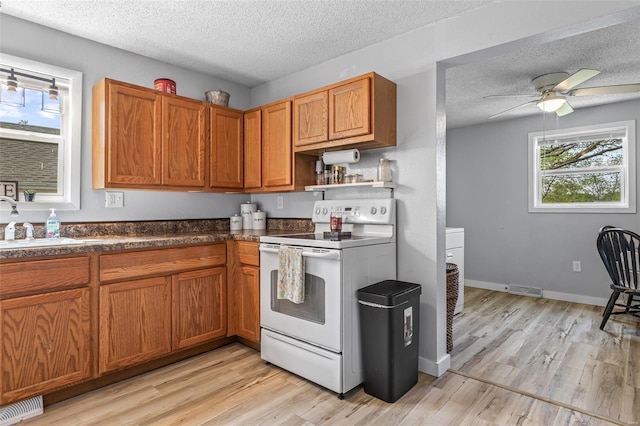 kitchen with a textured ceiling, visible vents, electric stove, and a sink