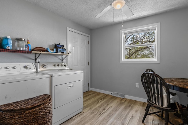 washroom with a textured ceiling, light wood-style flooring, visible vents, separate washer and dryer, and laundry area