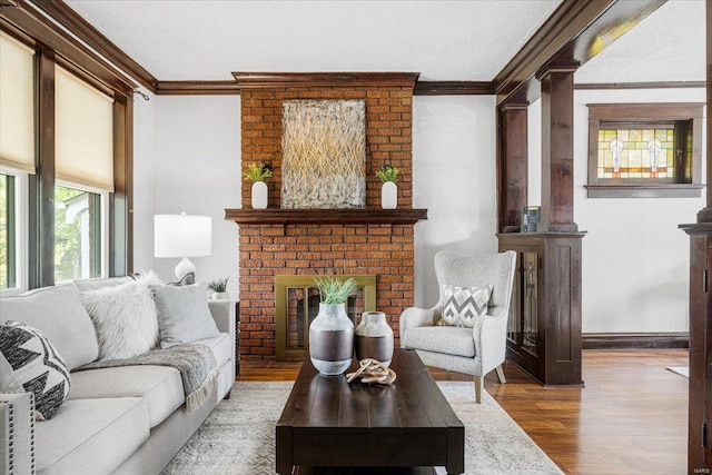living area with baseboards, ornamental molding, wood finished floors, and a fireplace