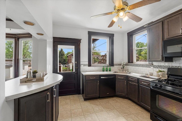 kitchen with a sink, light countertops, black appliances, and a wealth of natural light