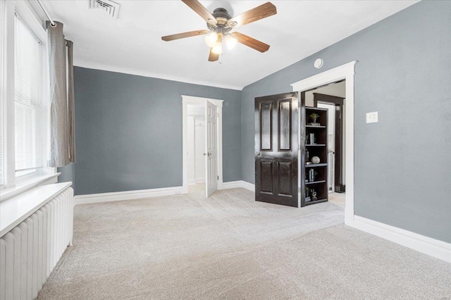 spare room with carpet floors, ceiling fan, visible vents, and radiator