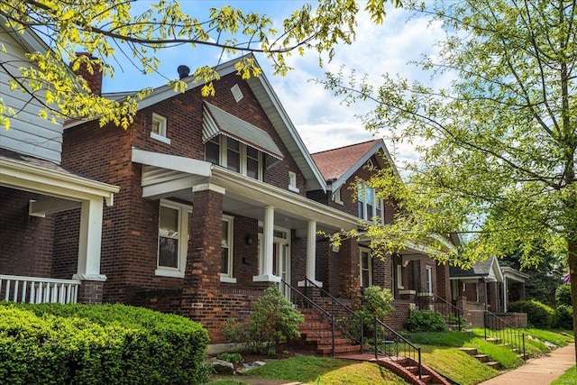 view of home's exterior with stairs, a chimney, a porch, and brick siding