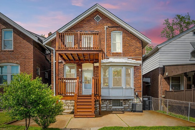 traditional-style house featuring brick siding, central AC unit, and fence