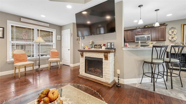 kitchen with a breakfast bar area, stainless steel microwave, wood-type flooring, and baseboards