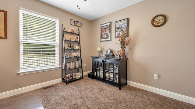 interior space featuring baseboards, visible vents, ceiling fan, and carpet flooring