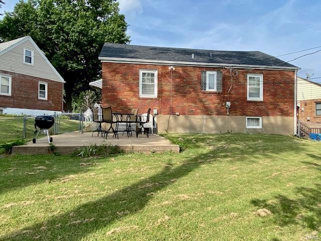 rear view of property featuring a patio area, roof with shingles, fence, a yard, and brick siding