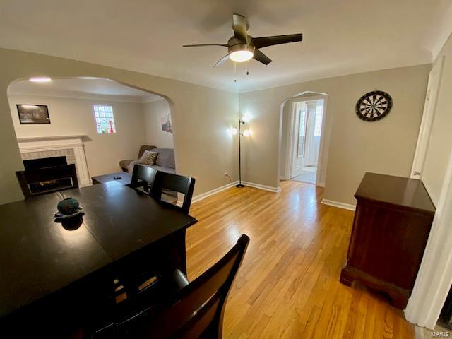 dining room featuring a tile fireplace, arched walkways, ceiling fan, and a wealth of natural light