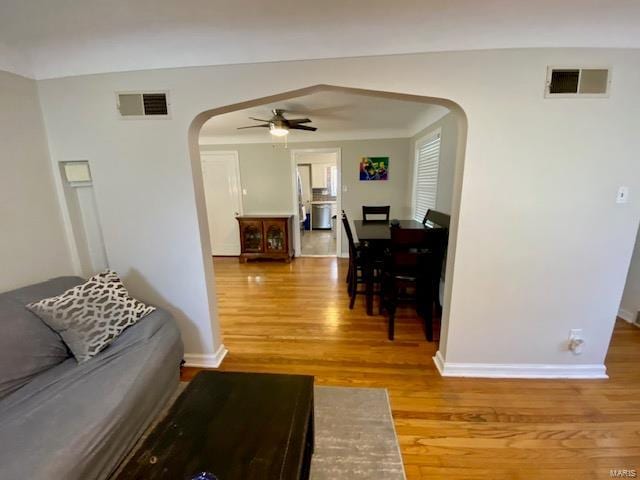 living area featuring visible vents, arched walkways, ceiling fan, and wood finished floors