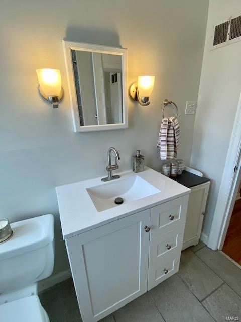 bathroom featuring toilet, visible vents, vanity, and tile patterned flooring