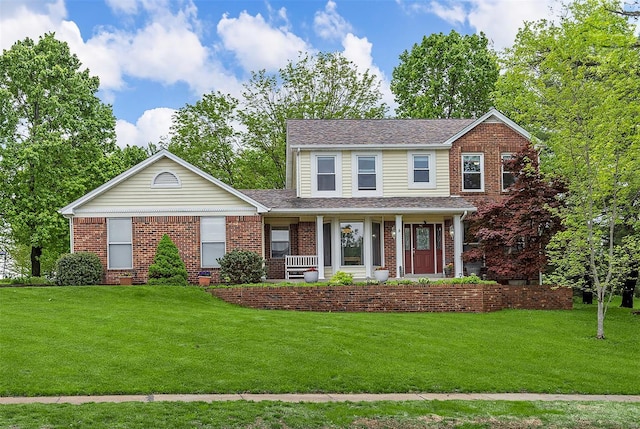 view of front of property featuring a porch, a front lawn, and brick siding