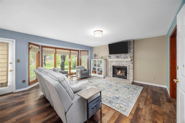 living area with a large fireplace, dark wood-style flooring, and baseboards