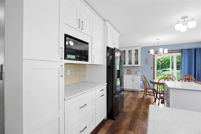 kitchen with an inviting chandelier, black fridge with ice dispenser, glass insert cabinets, dark wood-type flooring, and backsplash