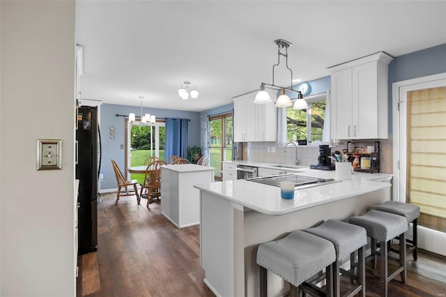 kitchen featuring a sink, cooktop, white cabinetry, light countertops, and freestanding refrigerator