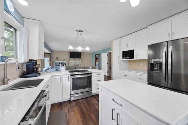 kitchen featuring dark wood-style floors, a sink, backsplash, white cabinetry, and appliances with stainless steel finishes