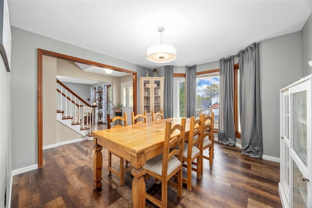 dining space featuring stairs, dark wood-style flooring, a wealth of natural light, and baseboards
