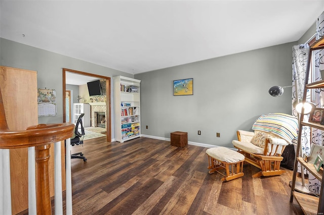 home office with wood finished floors, baseboards, and a brick fireplace