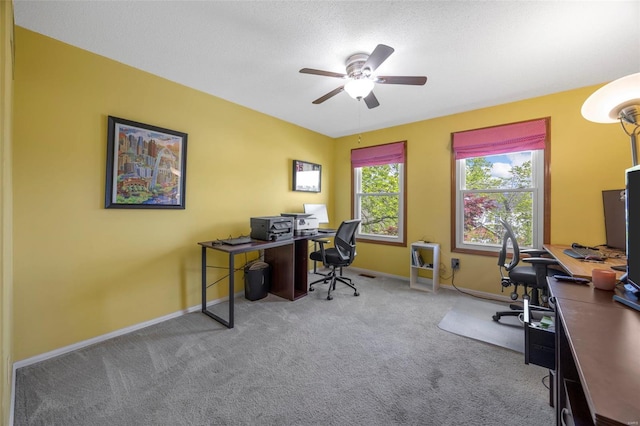 carpeted office space featuring a ceiling fan and baseboards