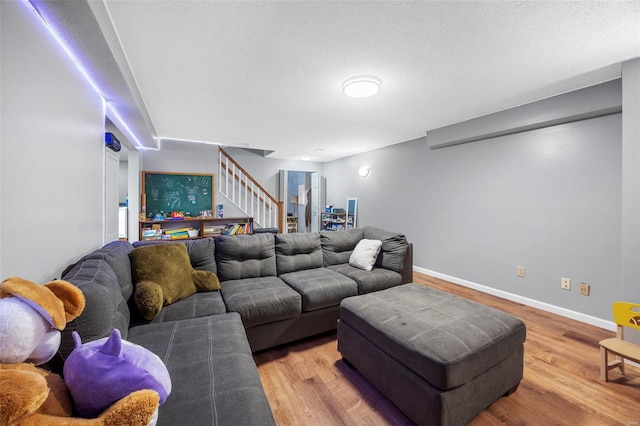 living room with stairs, a textured ceiling, wood finished floors, and baseboards