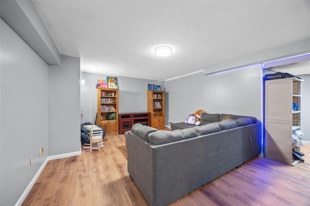 living area featuring a textured ceiling, wood finished floors, and baseboards
