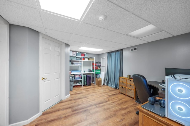 office featuring a paneled ceiling, visible vents, and wood finished floors