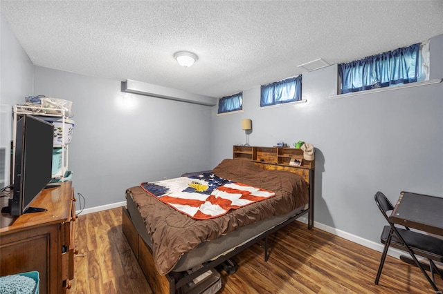 bedroom featuring a textured ceiling, wood finished floors, and baseboards