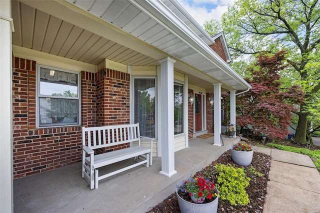 property entrance with covered porch and brick siding