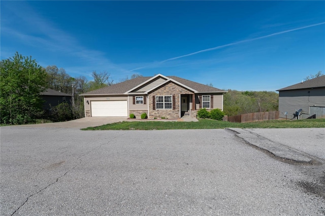 single story home featuring fence, concrete driveway, stone siding, and a garage